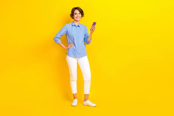 在智能手机社交媒体上贴出的漂亮女孩Bob发型 穿着蓝色衬衫 背景为黄色的全副照片 — 图库照片