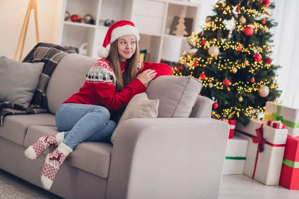 Full body photo of minded peaceful girl sit cozy couch think imagine warm newyear atmosphere indoors.