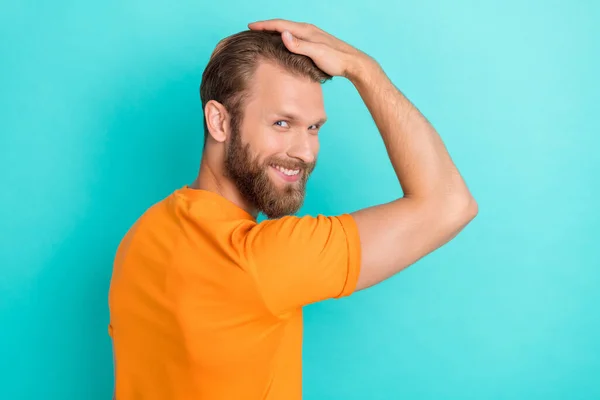 ブロンド毛のあるハンサムな正男の肖像画は オレンジ色のTシャツホールド手で頭の上に新しいヘアスタイルを着用します — ストック写真