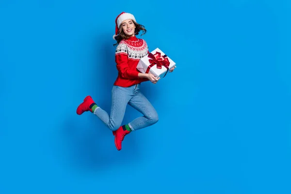 全长照片 滑稽甜美的女士穿着华丽的饰物毛衣跳着高举圣诞礼物空旷的空间孤立的蓝色背景 — 图库照片