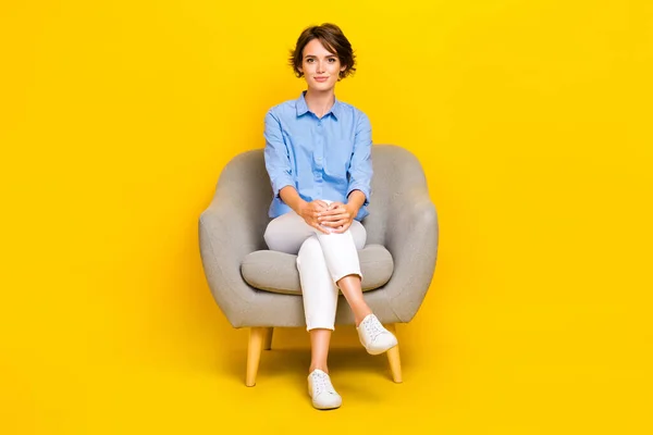 全长照片严肃自信的女孩穿着蓝色有休息沙发孤立的黄色背景 — 图库照片