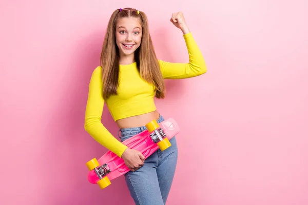 兴奋的幸运女学生身穿黄色庄稼顶部滑板上升的拳头孤立的粉色背景照片 — 图库照片