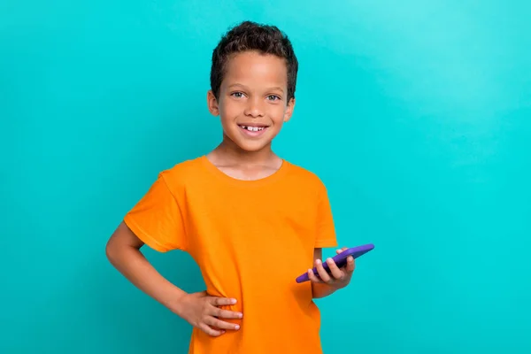 stock image Photo of sweet charming little guy dressed orange t-shirt typing instagram twitter facebook modern device isolated teal color background.