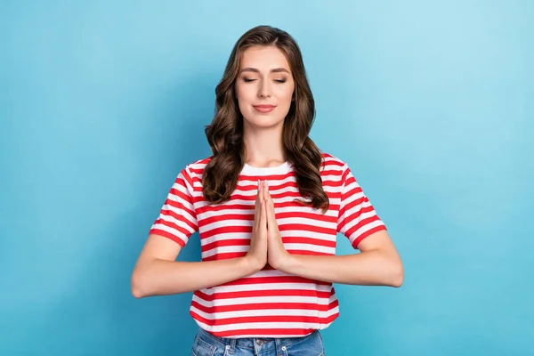 Photo of pretty lovely lady wear striped stylish clothes palm arm together praying peace stop war isolated on blue color background.