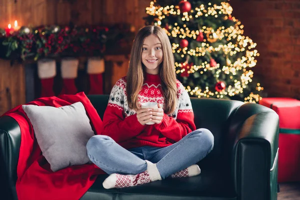フルサイズの写真の愛らしい正の女の子座ってソファ腕ホールドホットチョコレートマグカップ楽しむ魔法の精神の家屋内 — ストック写真