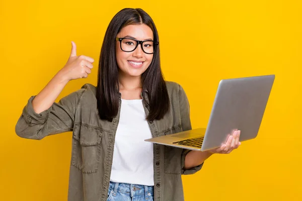 穿着卡其布衬衫的积极乐观的女人的画像表现得就像一个好工作 拿着用黄色背景隔开的笔记本电脑 — 图库照片