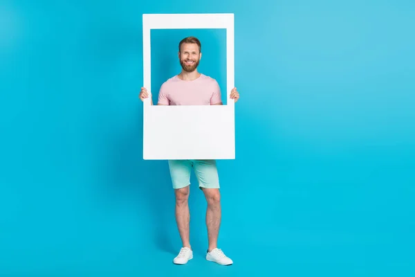Full length photo of nice young man hold social media post photo frame model wear trendy pink outfit isolated on cyan color background.
