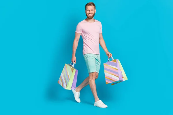 全长照片 漂亮的年轻人扛着购物袋横幅 穿着时髦的粉红色衣服 背景是青色的 — 图库照片