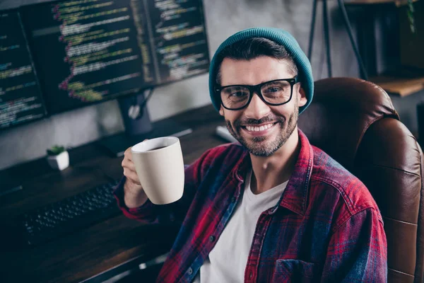 照片上 一个快乐而积极的家伙穿着眼镜 在家里的工作站里享用美味的热饮料 — 图库照片
