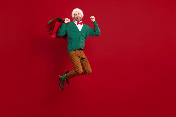 フルボディ写真のファンキージャンプ空気励起サンタクラス恋人男上げる拳アップ冬のシーズン安い服ショッピング孤立した上の赤の色の背景 — ストック写真