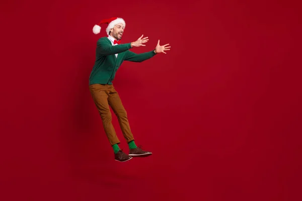 フル長さの写真のクリスマス男身に着けているサンタ帽子ジャンプ空気欲しい抱擁彼の望ましい願いプレゼント見える空のスペースに隔離された赤の色の背景 — ストック写真