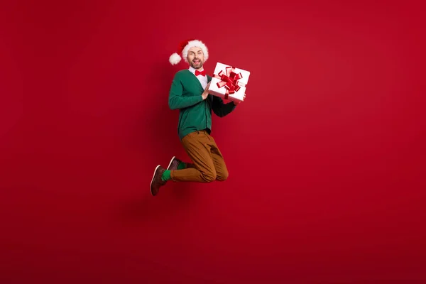 明るい狂気の人ジャンプ手ホールドのフルサイズの肖像画は赤の色の背景に隔離された新しい年のギフトボックスを受け取ります — ストック写真