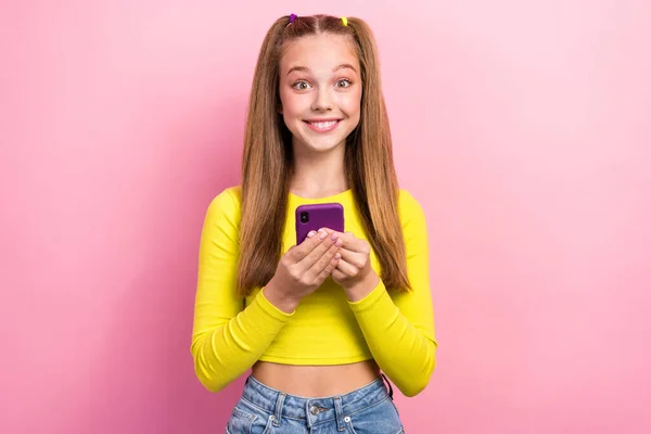 快乐可爱的女士身穿黄色时髦衬衫的照片 手持现代装置满足快速4G连接 与粉色背景隔离 — 图库照片