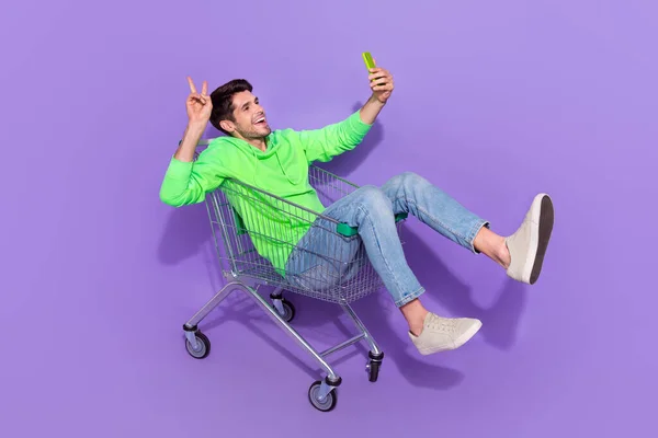 全长照片兴奋酷的家伙穿上霓虹灯运动衫购物托盘骑V字牌记录视频Vlog孤立的紫罗兰背景 — 图库照片