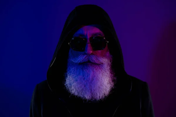 Photo of mysterious handsome pensioner guy wear black hoodie glasses bad santa claus isolated dark blue color background.