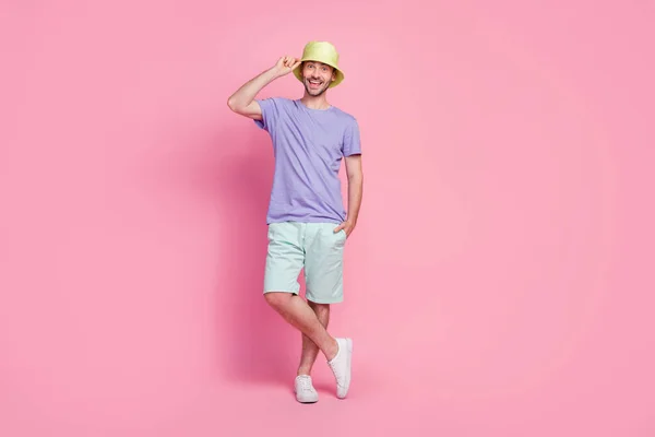 ハンサムな若い男のタッチの帽子のフルサイズの写真は ピンクの色の背景に隔離された流行の青い服を身に着けているサンバスショッピングプロモーションをお楽しみください — ストック写真