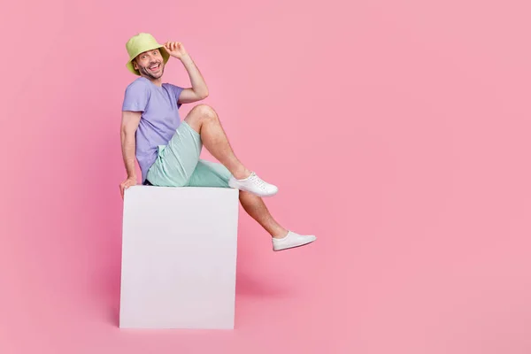 ハンサムな若い男のフルサイズの写真座っている空白のバナーキューブショッピングプロモーション服トレンディーな青の服ピンク色の背景に隔離 — ストック写真