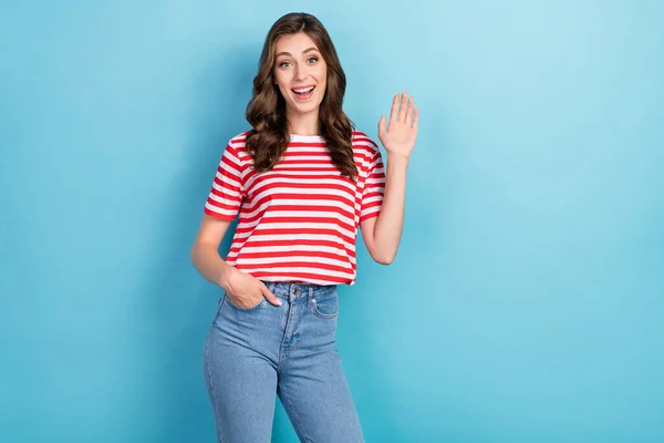 Photo of cute joyful lady wear fashionable clothes raise arm glad see meet you say hello empty space isolated on blue color background.