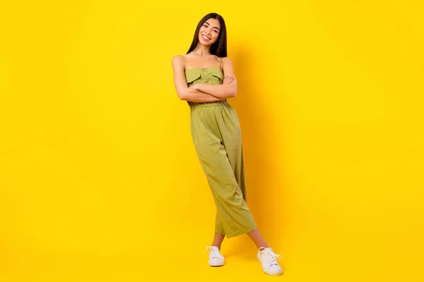 Full body portrait of pretty cheerful indonesian person folded arms posing isolated on yellow color background.