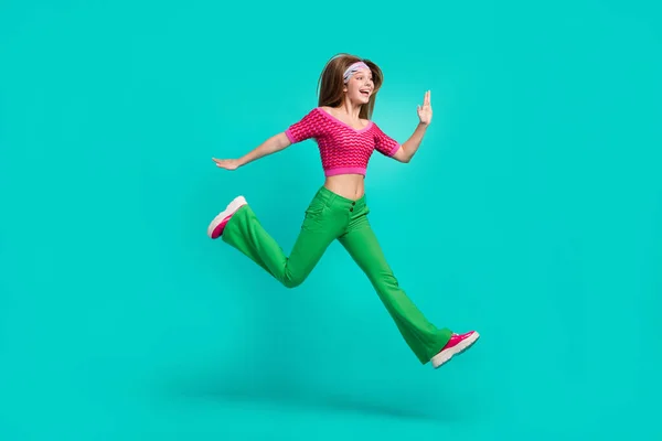 stock image Full length photo of sweet impressed schoolgirl wear pink crop top flare trousers jumping high isolated turquoise color background.