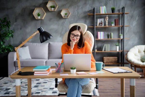 照片中快乐漂亮的女老板穿着橙色套头衫坐在桌子上聊天同事们现代Macbook室内工作站 — 图库照片