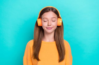 Photo of young funny dreamy girl wear orange wireless earbuds closed eyes listen her favority soundtrack isolated on aquamarine color background. clipart