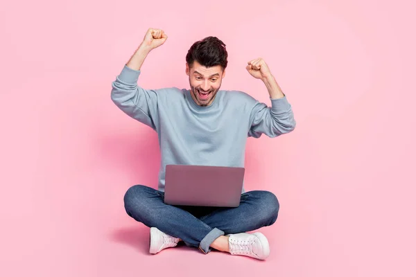 Full body photo of nice young guy raise fists win prize money remote casino dressed trendy blue clothes isolated on pink color background.
