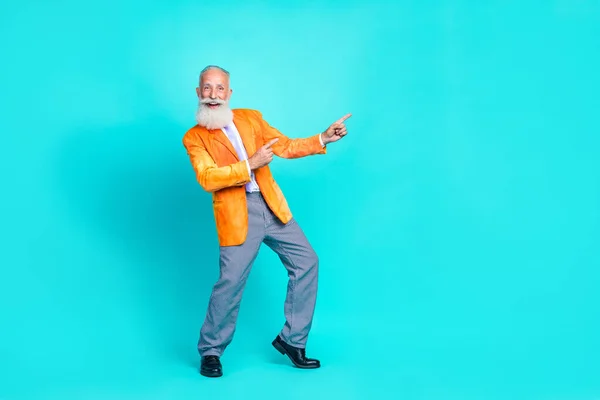 全长照片 开朗凉爽的退休男子穿着鲜艳的橙色夹克 两指空空的地方 孤立的绿松石色背景 — 图库照片