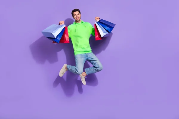 全长照片 兴奋而滑稽的男人穿着绿色的上升便宜货跳过空旷的空间孤立的紫色背景 — 图库照片