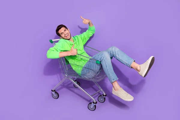 可爱的时髦男子身穿绿色连帽衫的超市托盘骑手的全长照片 照片上的大拇指伸出孤立的紫色背景 — 图库照片