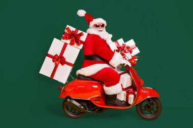 Full size profile side photo of white grey hair bearded santa claus ride motorbike deliver x-mas christmas gifts on noel night wear headwear isolated bright shine color background clipart