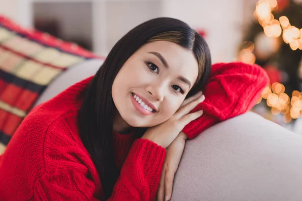 漂亮而满意的可爱女人的画像 一头直发 身穿红色针织套头衫 手放在沙发上 脸朝下躺在屋里 — 图库照片