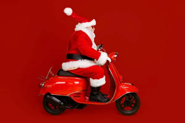 相貌侧面看他那可爱又胖又厚的白发苍苍的圣诞老人骑摩托车速速赶忙购物甩卖帽球飞孤立明亮鲜亮发亮的黄色底色 — 图库照片