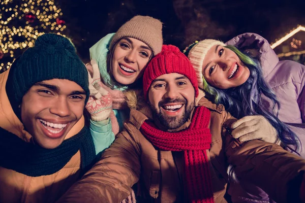 照片上 四个时髦快乐的好友穿着防风衣 一起拥抱在城市市场公园外录制的视频圣诞博客 — 图库照片