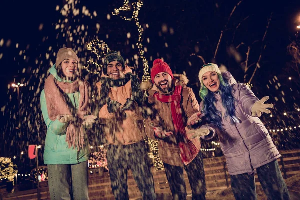 Photo of young excited people wear warm coats jackets throwing snow camera near big capital center tree buy more christmas souvenirs outdoors.
