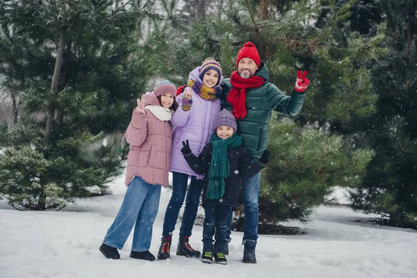 Photo of caring family mommy daddy little kids enjoy x mas countryside travel vacation in woods make v sign.