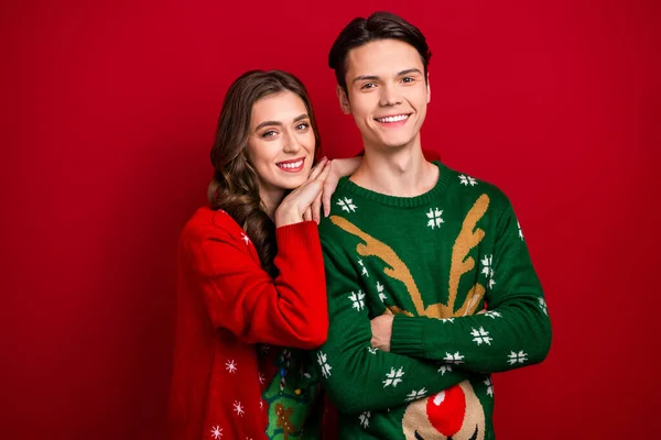 Photo of pretty cute couple wife husband wear ugly sweaters enjoy spend weekend vacation together isolated on red color background.