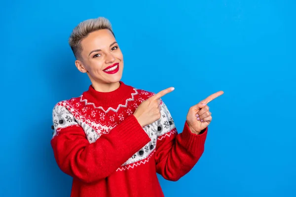 Photo of smiling pretty woman direct fingers copyspace recommend new year sweaters shop cheap prices isolated on bright blue color background.