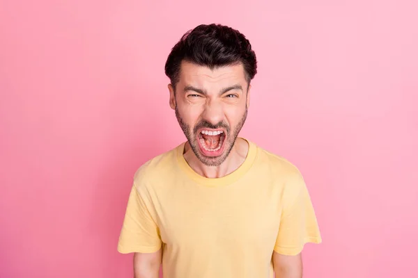 怒り狂った男の肖像画でスタイリッシュな髪型は ピンクの色の背景に隔離された黄色のTシャツ大声で叫んで口を開きます — ストック写真