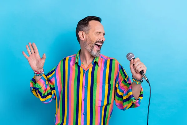 興奮したプロの歌手カラオケ男の写真縞模様のヴィンテージカラフルなシャツを着用青い色の背景に孤立マイクセレナーデを保持 — ストック写真