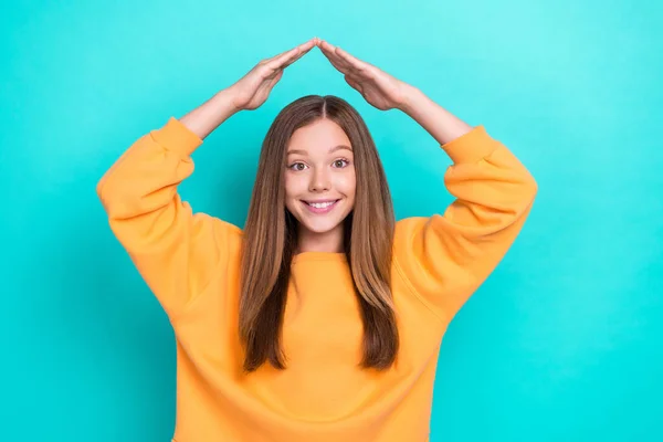 Photo of young funny good looking cute girl teenager showing safety house symbol protect herself smiling good mood isolated on cyan color background.