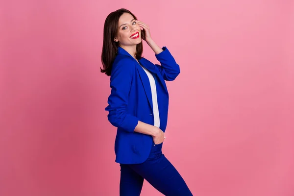 若い豪華なビジネス女性の写真は青の正式な衣装を身に着けています彼女の髪型に触れる彼女の満足笑顔ポーズピンク色の背景に孤立 — ストック写真