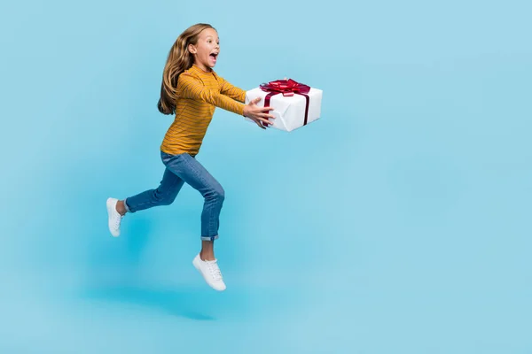 兴奋的疯狂女孩手握着礼品盒的全长肖像跳跃冲刺与蓝色背景隔离 — 图库照片