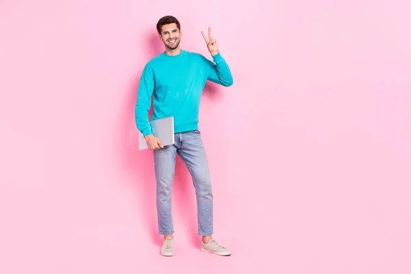 Vサインを示すノートパソコンの起業家を保持ハンサムな若い男のフルボディ写真Vサインはピンク色の背景に隔離されたトレンディーな青の服を身に着けて — ストック写真