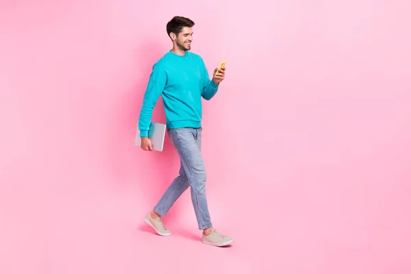 読書ニュースを入力してラップトップデバイスを保持素敵な若い男の完全な長さの写真ピンク色の背景に隔離されたトレンディーな青の服を着用 — ストック写真