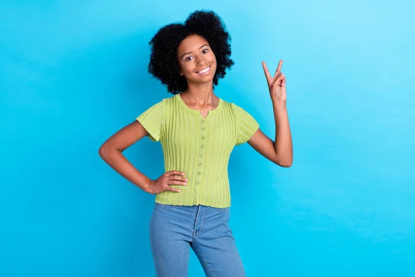 青い色の背景に隔離された腰の上にV Signの手を示す説得力のある緑のTシャツと楽観的な素敵な肯定的な女の子の写真 — ストック写真