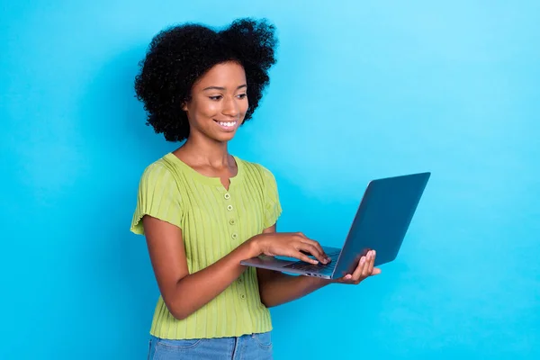 照片上积极聪明的女孩穿着烫发的绿色T恤 抱着笔记本电脑在蓝色背景下做家庭作业 — 图库照片