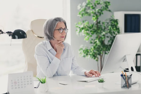 图为专注于创业的退休妇女在成功的老板手下工作的照片 明亮的现代工作站用计算机打字 — 图库照片