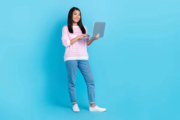 Full length photo of young korean freelancer lady hold her laptop video meeting conference with coworkers isolated on bright blue color background.