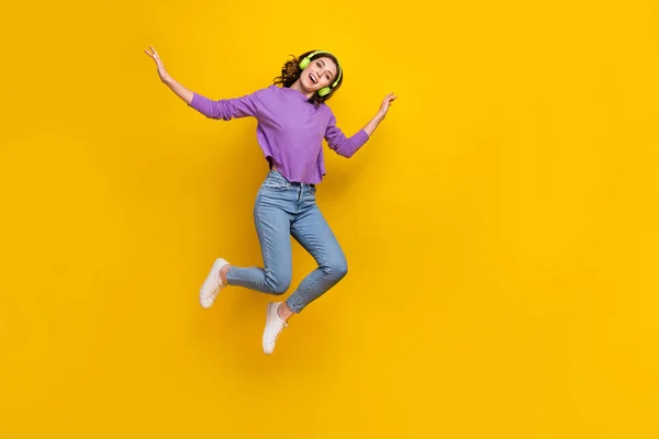 明るいです女の子楽しいです好きな音楽ジャンプ孤立した上の黄色の色の背景 — ストック写真